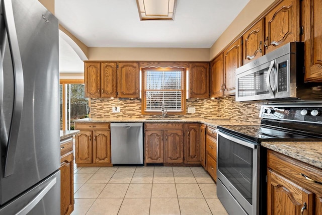 kitchen featuring a sink, brown cabinets, a healthy amount of sunlight, and stainless steel appliances