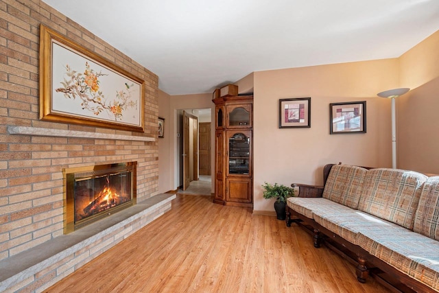 living room with baseboards, a fireplace, and light wood-style flooring
