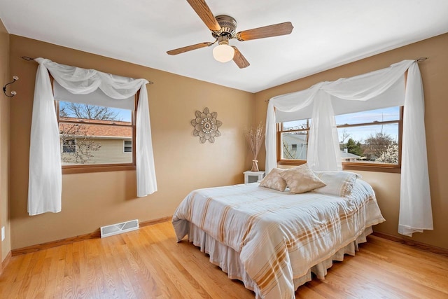 bedroom with baseboards, ceiling fan, light wood-style flooring, and visible vents