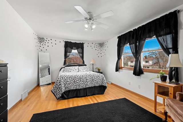 bedroom with baseboards, ceiling fan, visible vents, and wood finished floors