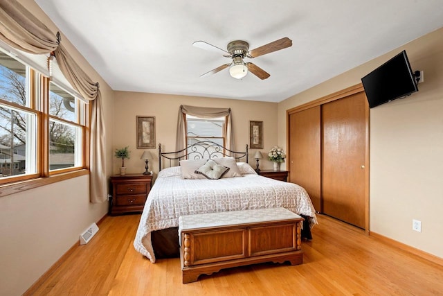 bedroom with a ceiling fan, visible vents, baseboards, a closet, and light wood-style flooring