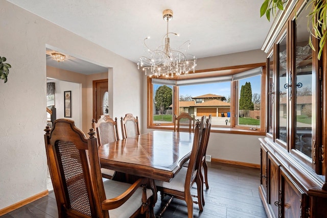 dining area featuring baseboards, hardwood / wood-style floors, and an inviting chandelier