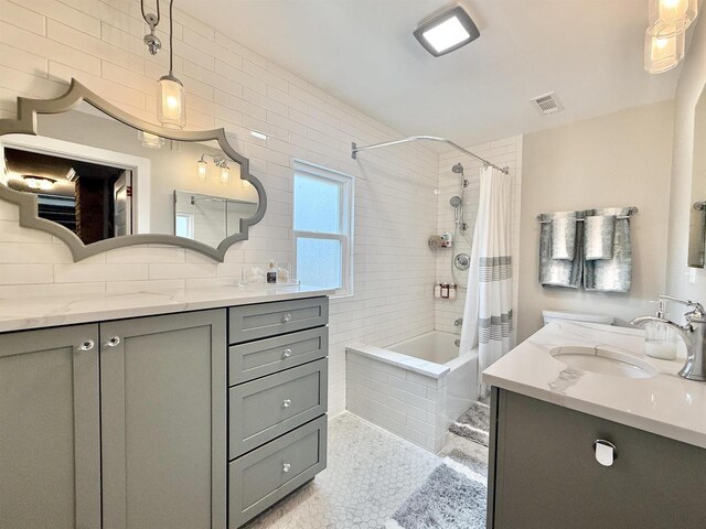 852 Sherwood Dr NW, Beloit, WI 53511 - full bathroom featuring visible vents, tasteful backsplash, vanity, tile patterned floors, and tiled shower / bath combo