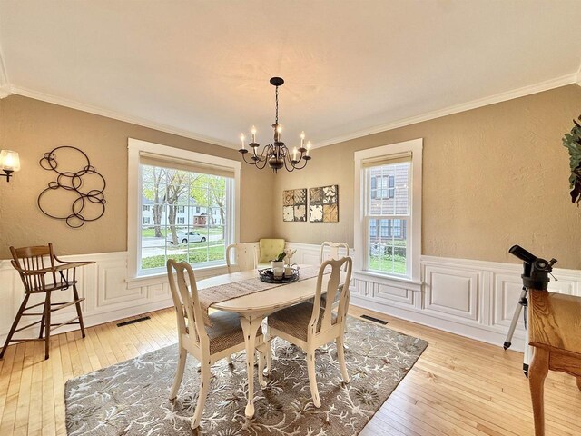 852 Sherwood Dr NW, Beloit, WI 53511 - dining area featuring visible vents, light wood-style flooring, crown molding, and a notable chandelier