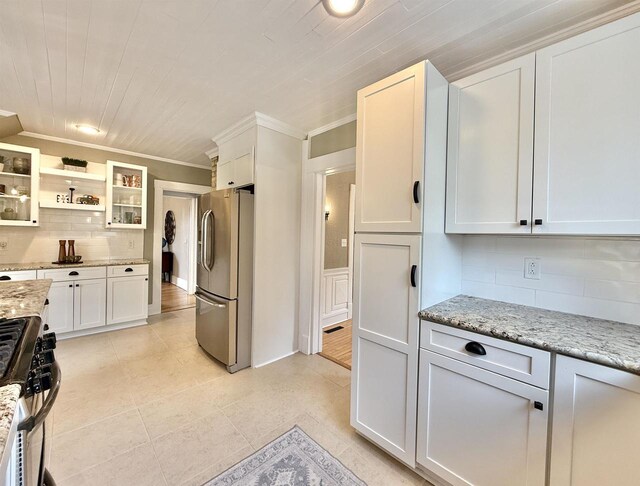 852 Sherwood Dr NW, Beloit, WI 53511 - kitchen with appliances with stainless steel finishes, tasteful backsplash, light stone counters, glass insert cabinets, and white cabinetry