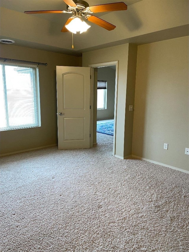 spare room featuring carpet floors, a ceiling fan, and baseboards