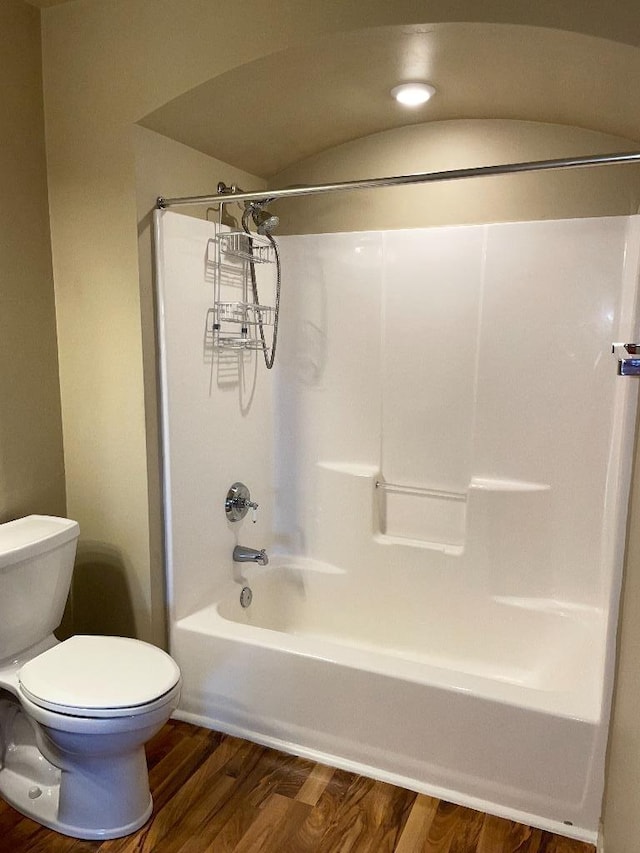 bathroom with shower / bathtub combination, toilet, and wood finished floors