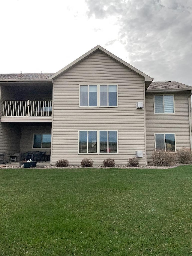 back of house with a yard and a balcony