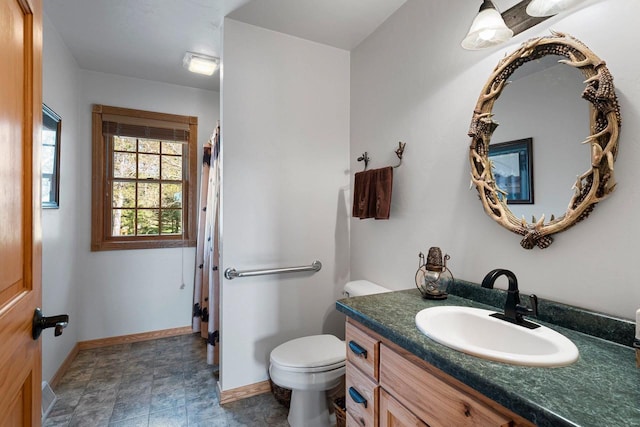 bathroom with baseboards, vanity, toilet, and curtained shower