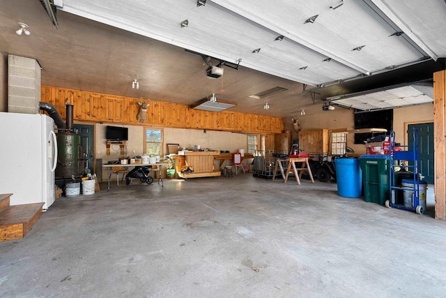 garage featuring a workshop area, a garage door opener, and white fridge with ice dispenser