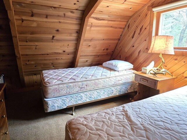carpeted bedroom with wooden walls, vaulted ceiling, and wooden ceiling