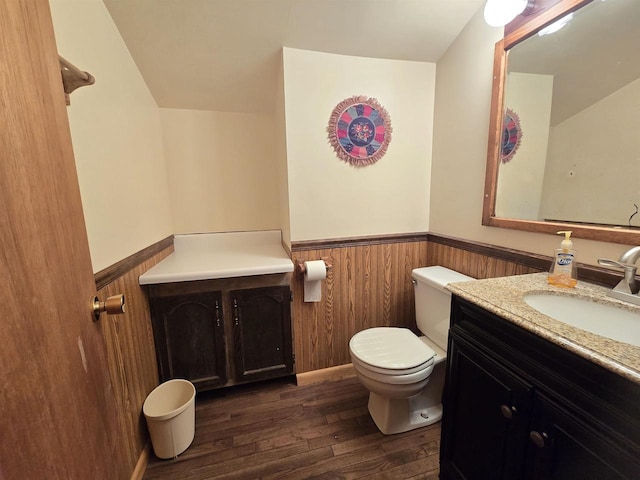 bathroom featuring wooden walls, wainscoting, vanity, wood-type flooring, and toilet