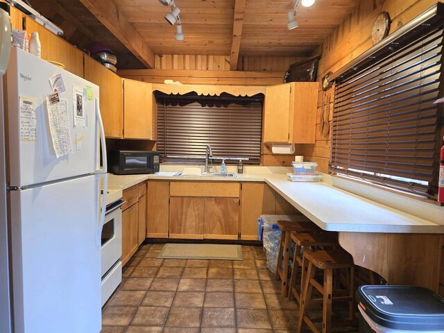 kitchen with a sink, white appliances, light countertops, rail lighting, and wooden ceiling