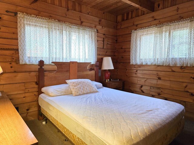 bedroom featuring wooden walls, wooden ceiling, and carpet floors
