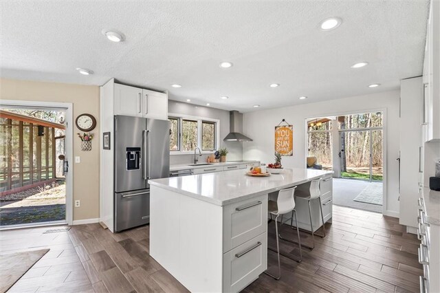 1206 Pinecrest Ln, New Richmond, WI 54017 - kitchen featuring wall chimney range hood, a sink, dark wood finished floors, a kitchen island, and high quality fridge