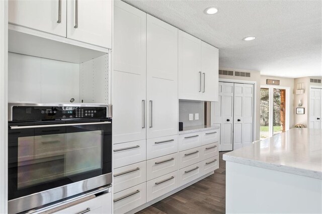 1206 Pinecrest Ln, New Richmond, WI 54017 - kitchen with a textured ceiling, dark wood finished floors, white cabinetry, and oven