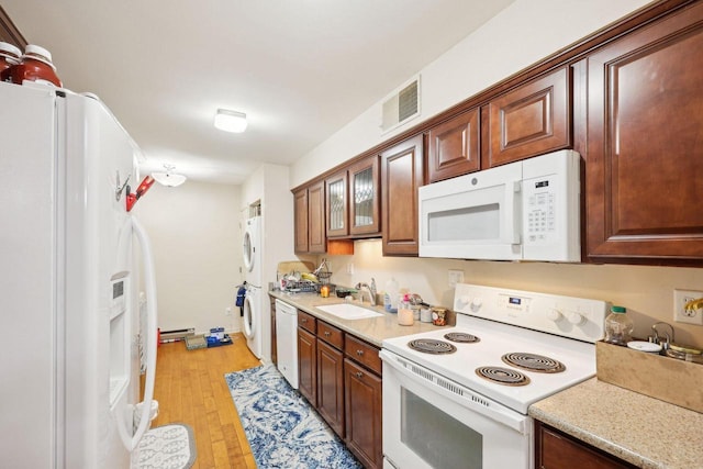 kitchen featuring visible vents, stacked washer and dryer, white appliances, light countertops, and a sink