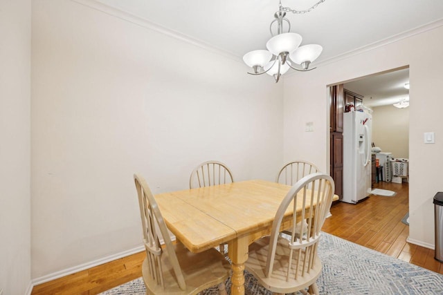 dining room featuring a notable chandelier, ornamental molding, and light wood finished floors