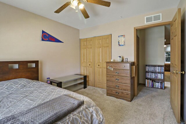 carpeted bedroom with a ceiling fan, visible vents, and a closet