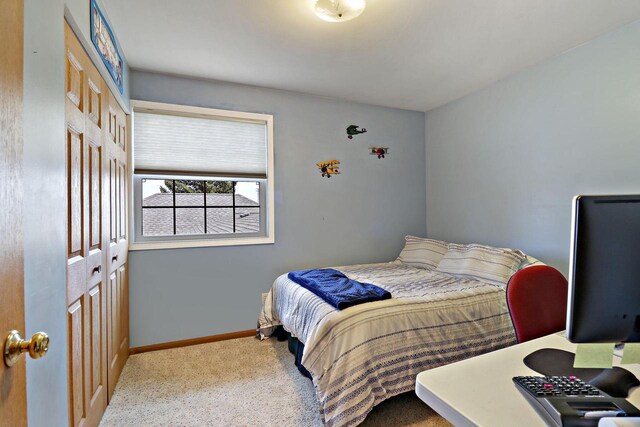 carpeted bedroom featuring baseboards and a closet