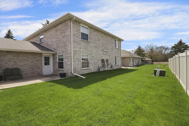 back of house with fence, a patio, a lawn, and brick siding