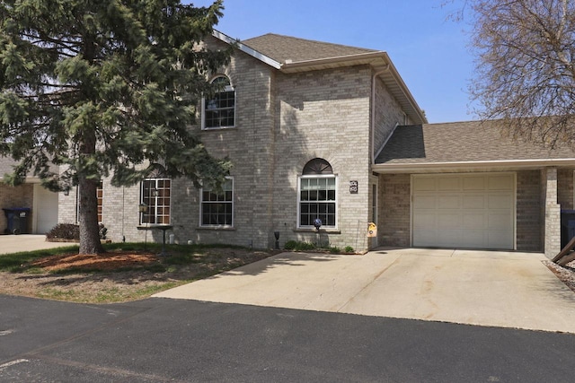 view of front of home featuring a garage, concrete driveway, roof with shingles, and brick siding