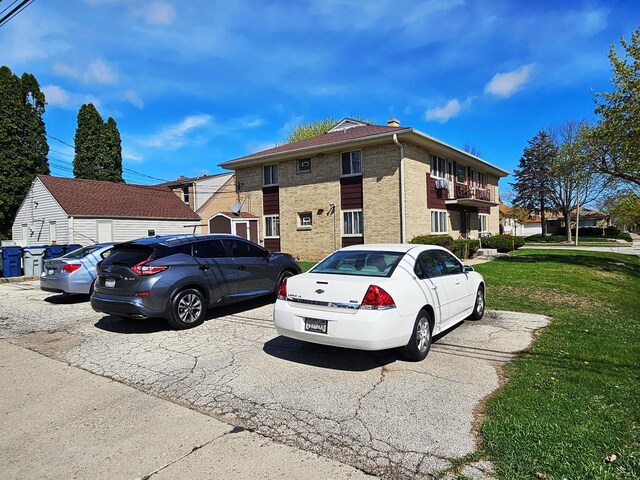 exterior space with a lawn, uncovered parking, and brick siding