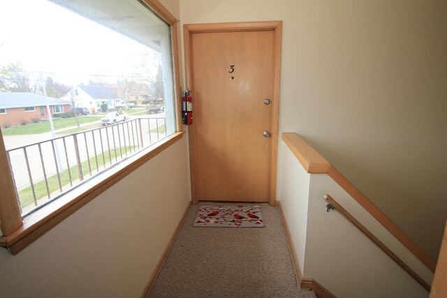 doorway to outside with baseboards and carpet flooring