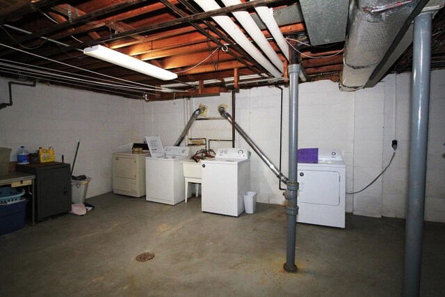 unfinished basement featuring washer and clothes dryer, a sink, and concrete block wall