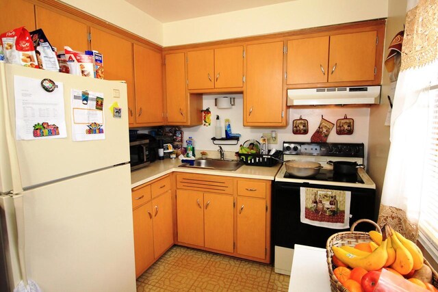 kitchen with electric range, a sink, light countertops, freestanding refrigerator, and under cabinet range hood