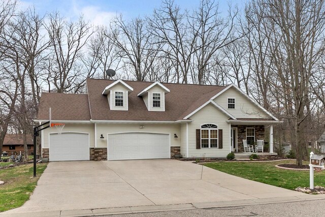 view of front facade featuring a garage, a porch, driveway, and stone siding