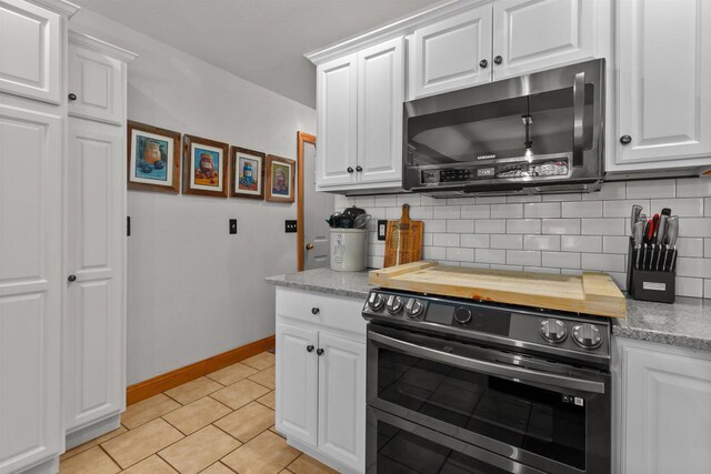 kitchen featuring decorative backsplash, butcher block counters, baseboards, white cabinetry, and double oven range