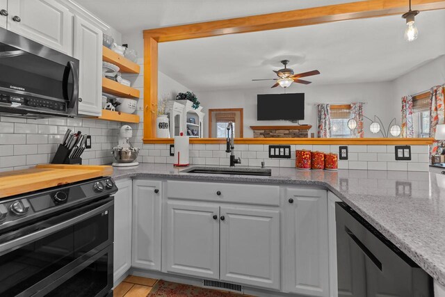 kitchen featuring decorative backsplash, a ceiling fan, a sink, a wealth of natural light, and double oven range