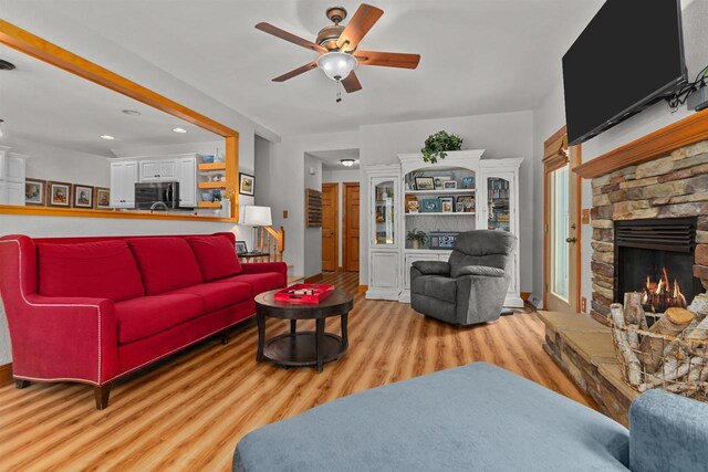 living area featuring a fireplace, a ceiling fan, recessed lighting, and wood finished floors