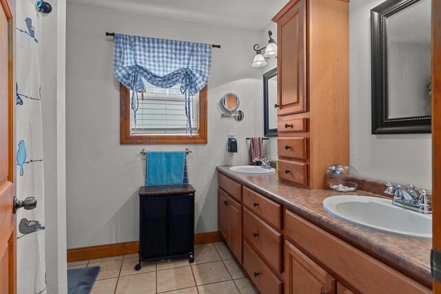 full bath with double vanity, a sink, and tile patterned flooring