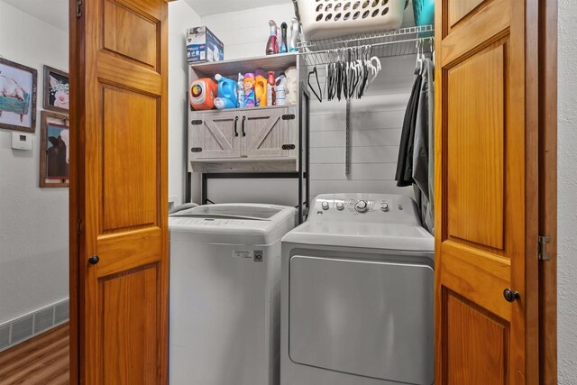 laundry room with separate washer and dryer, cabinet space, wood finished floors, and visible vents