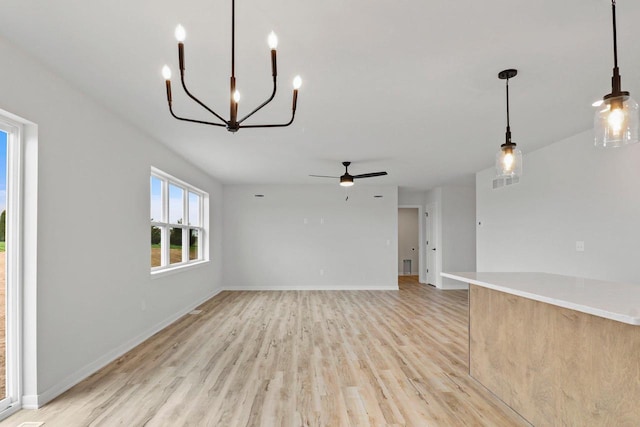 N6285 Blarney Stone Dr, Albany, WI 53520 - unfurnished living room featuring light wood-type flooring, baseboards, and ceiling fan with notable chandelier