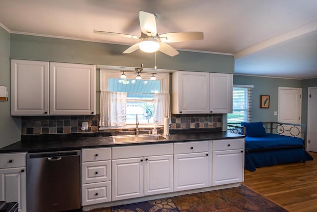 kitchen with crown molding, dark countertops, a sink, a ceiling fan, and stainless steel dishwasher
