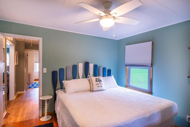bedroom with baseboards, multiple windows, wood finished floors, and attic access