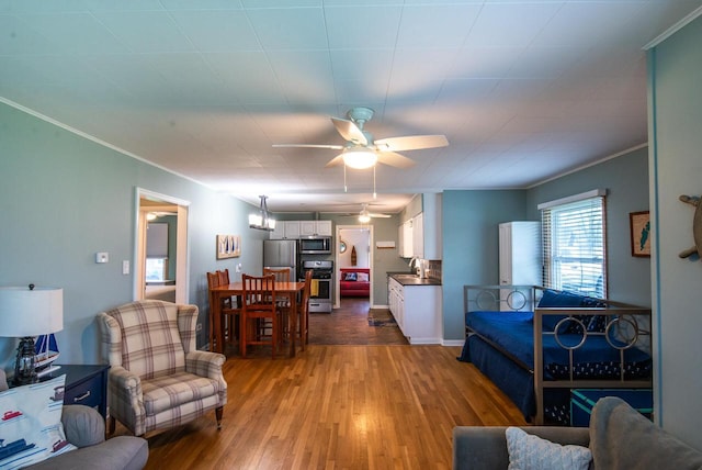 living area featuring crown molding, ceiling fan, and wood finished floors