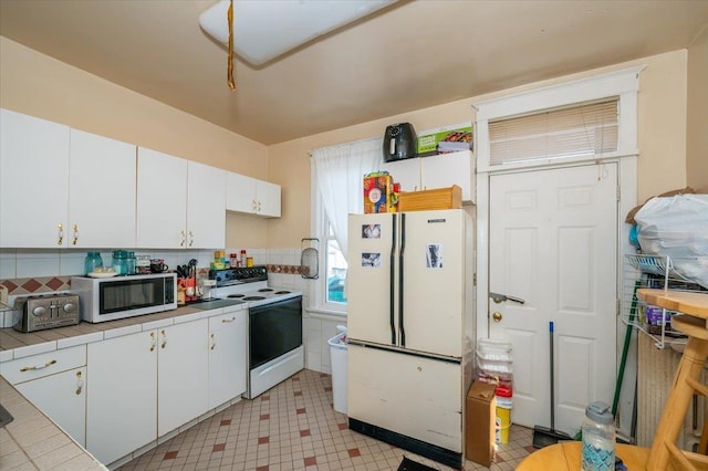 kitchen featuring a toaster, white appliances, light floors, tile counters, and white cabinets