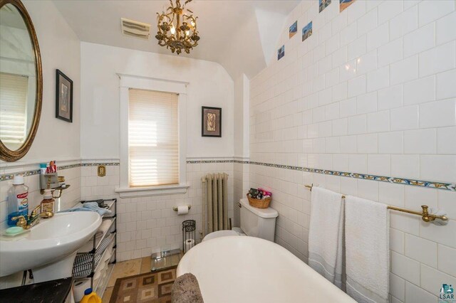 full bath featuring visible vents, a freestanding bath, tile walls, a chandelier, and radiator heating unit