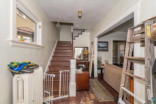 stairs with wood finished floors and radiator heating unit