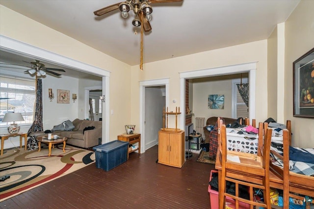 living room with a ceiling fan and dark wood-type flooring