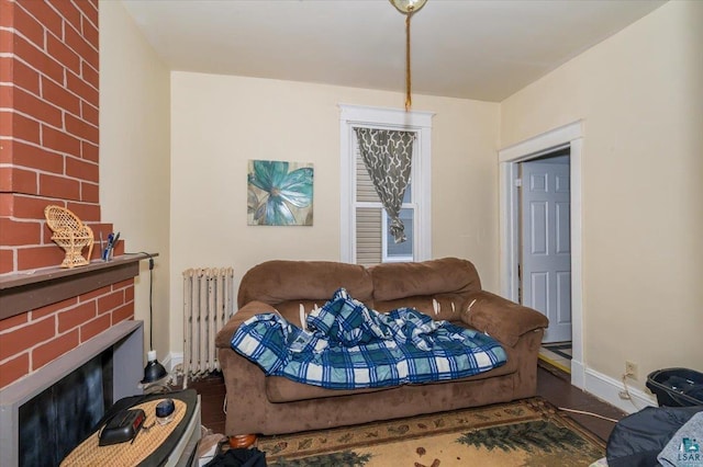 living area with radiator, baseboards, and a brick fireplace