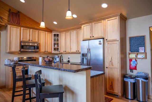 W5588 S Stone Gate Dr, New Lisbon, WI 53950 - kitchen with glass insert cabinets, a breakfast bar area, appliances with stainless steel finishes, vaulted ceiling, and light wood-style floors