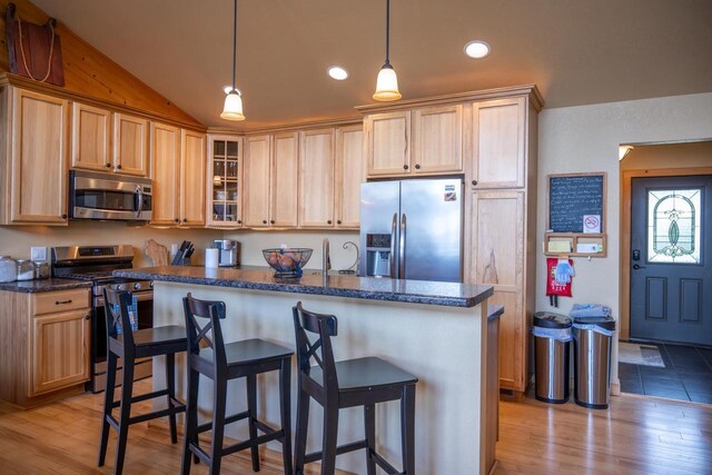 W5588 S Stone Gate Dr, New Lisbon, WI 53950 - kitchen featuring appliances with stainless steel finishes, vaulted ceiling, glass insert cabinets, a breakfast bar, and light wood-style flooring