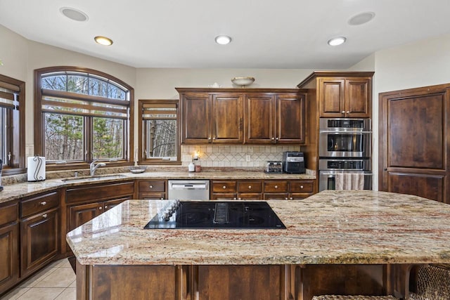 kitchen featuring a sink, appliances with stainless steel finishes, light stone countertops, and tasteful backsplash