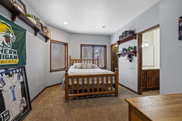 bedroom featuring connected bathroom, baseboards, and light colored carpet