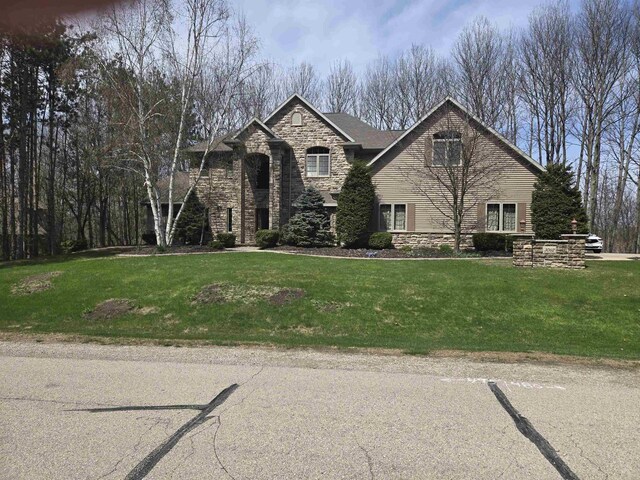 traditional home featuring a front yard and stone siding